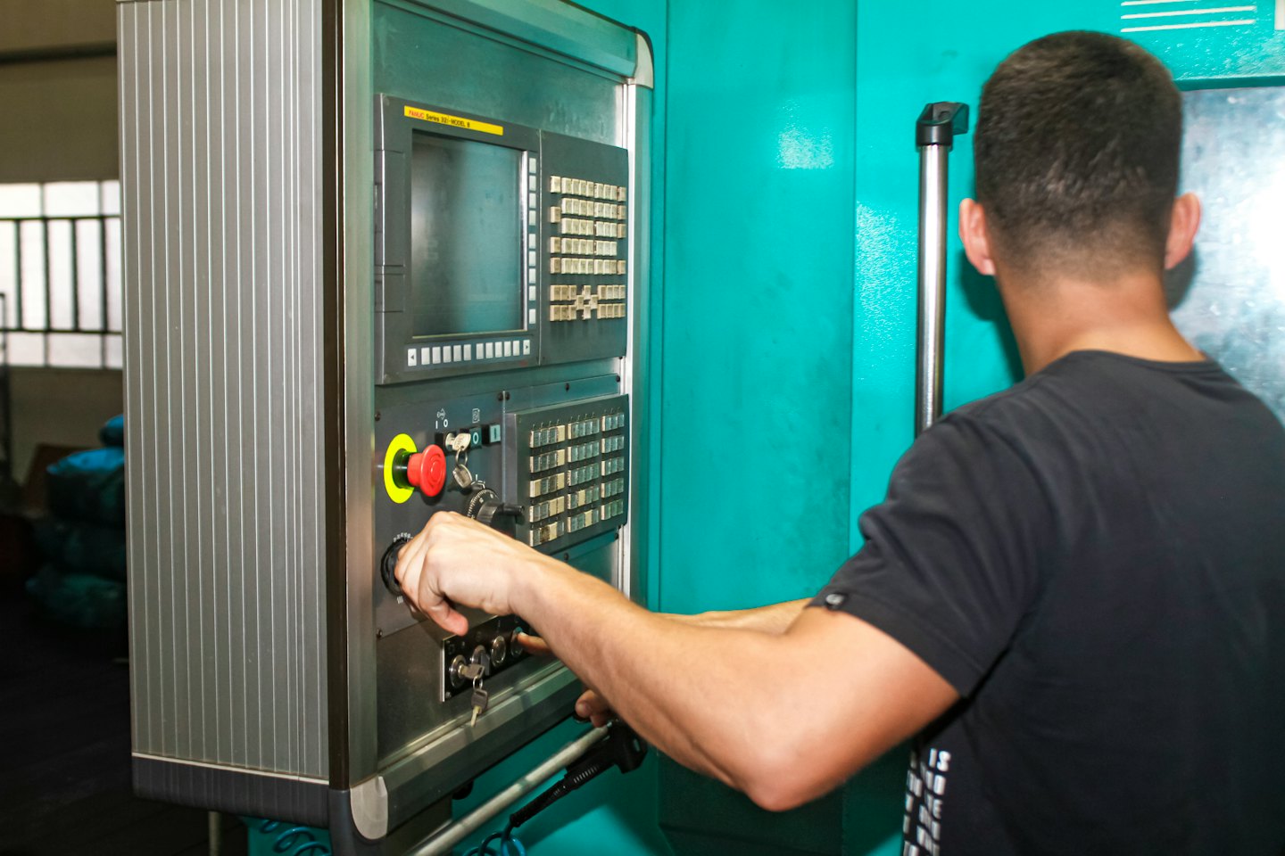Hands operating a factory machine control panel.